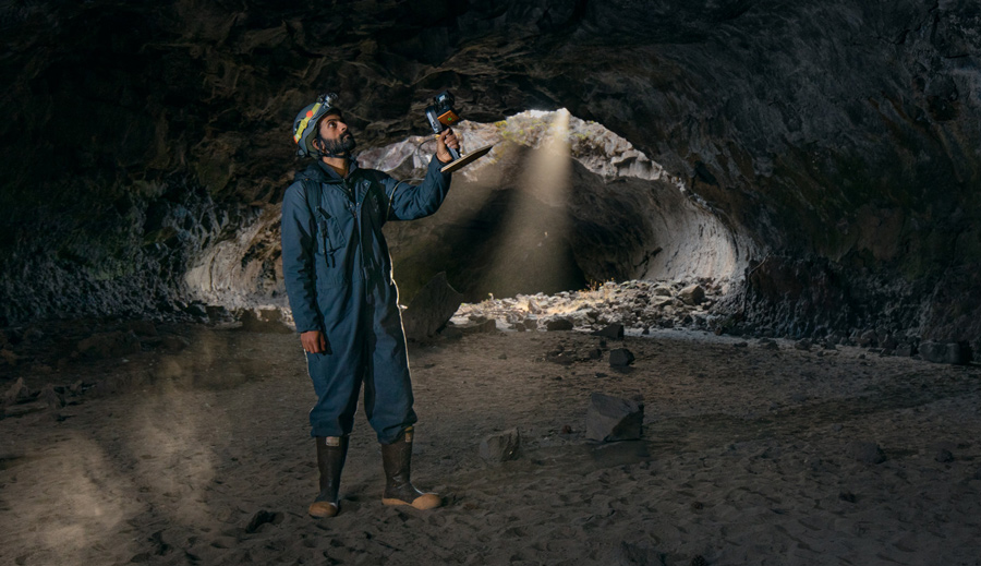 man filming from inside a cave
