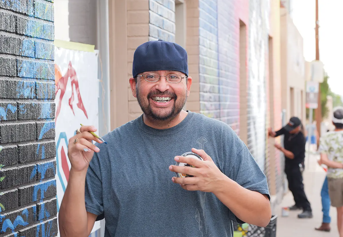 community member holding a paintbrush and smiling