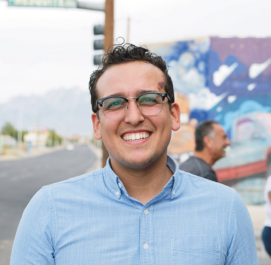 community member smiling at the paint event with the mural in the background