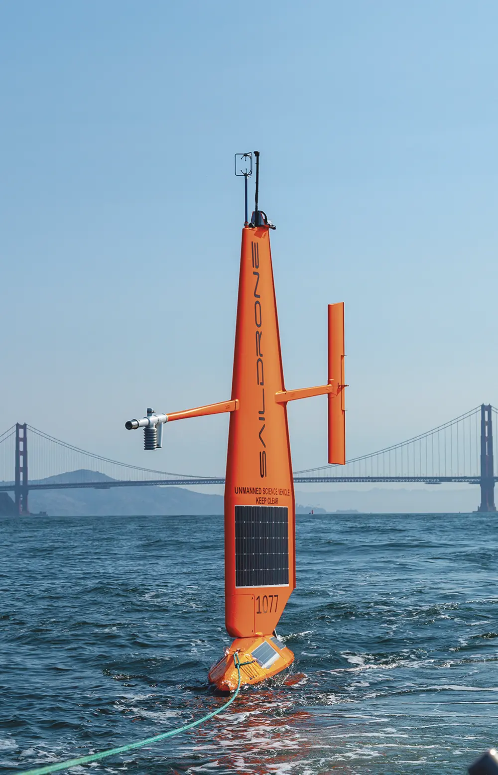 a bat detector mounted on a Saildrone autonomous vehicle sailing against the background of the Golden Gate Bridge and tethered to a rope that leads of frame