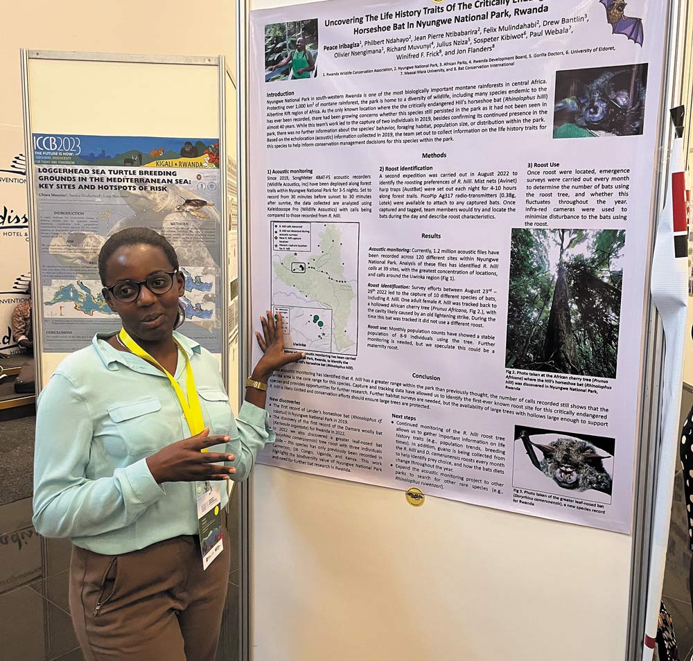 Peace Iribagiza standing beside a poster while speaking
