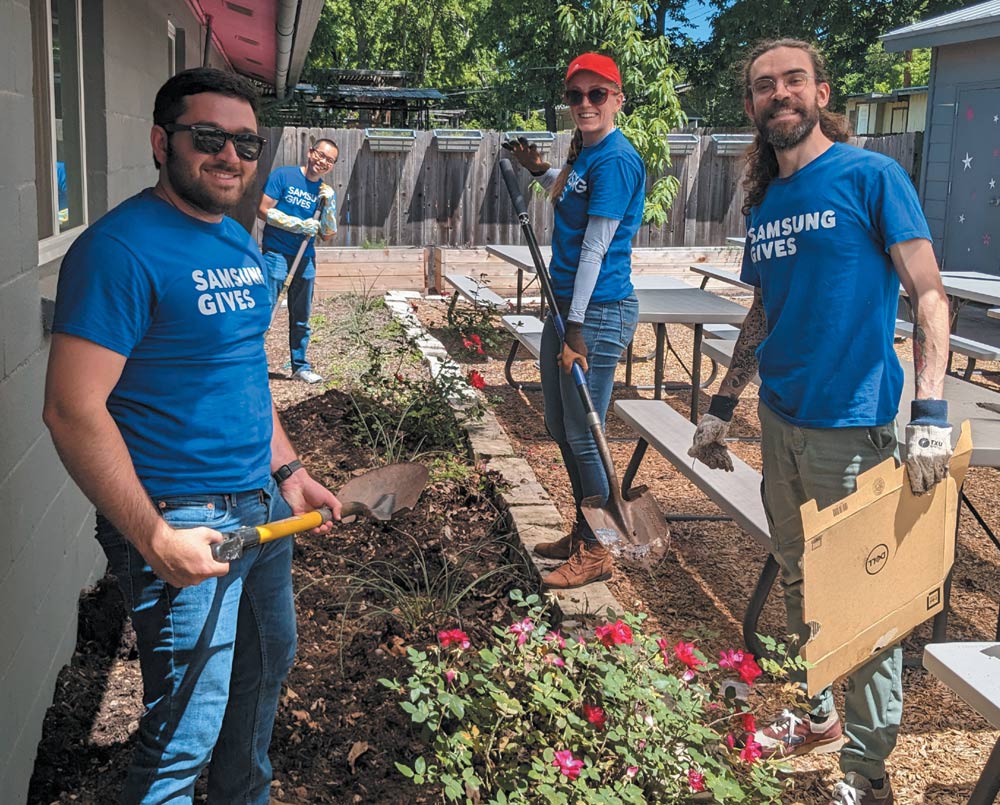 Four people gardening in matching "SAMSUNG GIVES" t-shirts.
