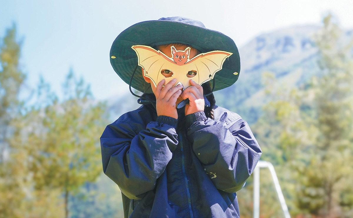 girl holding mask from the Bat Kit of Peru up to her face